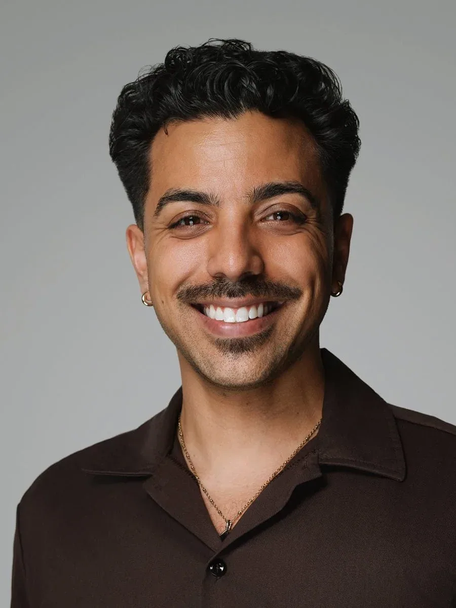 Man in a brown shirt against a grey background.