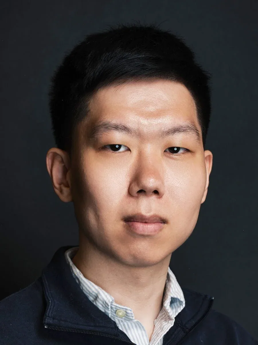 Man in a navy jacket against a dark background.
