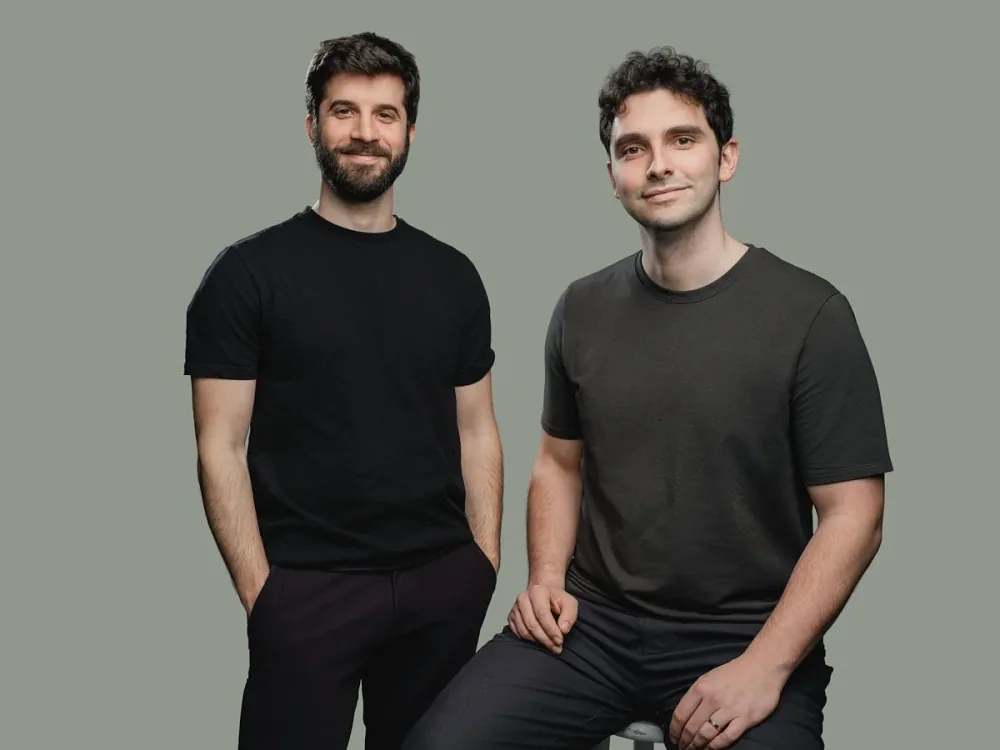 Two men photographed together against a muted green background.