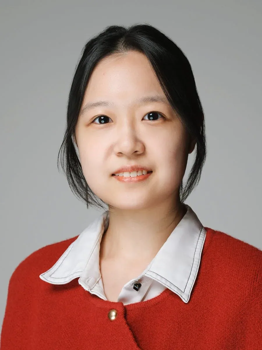 Woman in a red cardigan against a grey background.